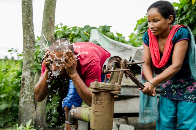 Person affected by leprosy Gobal with his wife getting water